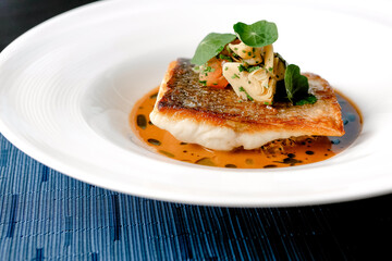 Snapper Fish in soy saunce with green leaves on a white plate