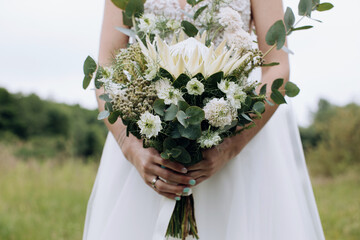 Beautiful wedding bouquet of white protea in the hands of the bride
