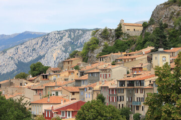 Fototapeta na wymiar View to the hillside houses and roofs of the french village Aiguines, Provence, France with the regional national park Verdon, canyon Gorge du Verdon in blurred background