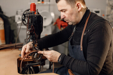 Leather craftsman working on a belt using a sewing machine