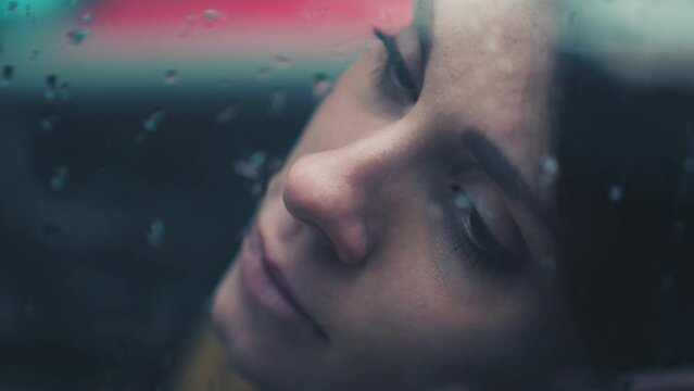 depressed woman in the car with her head leaning against the window looks away