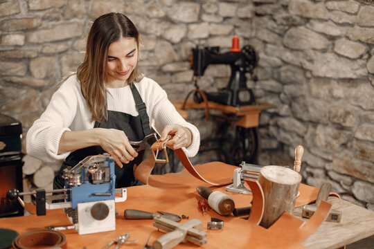Female leather craftsman working on a belt - Powered by Adobe