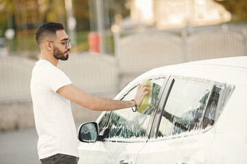 Indian man washing his white transportation on car wash