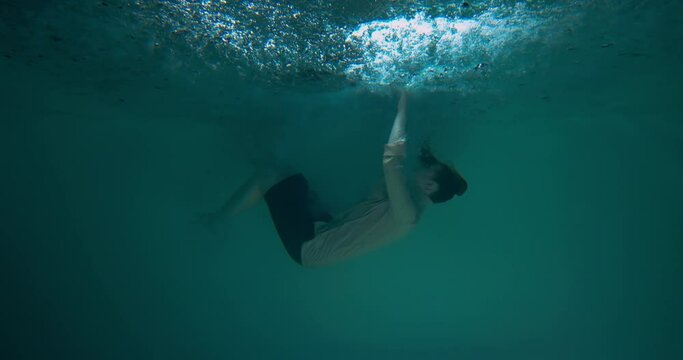 MENTAL BURNOUT Cinematic background of depressed woman in formal suit diving, sinking deep down underwater slow motion.