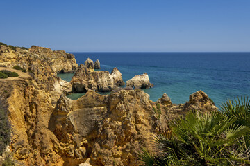 the idyllic Praia dos Tres Irmaos Beach surrounded by yellow cliffs and emerald sea in Portimao, Algarve, Portugal