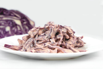 Red cabbage and red onion salad dressed with sour cream in a white plate. Red cabbage is rich in vitamins C and K, and contains a lot of anthocyanins and antioxidants.