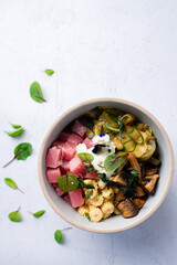 Organic food tuna poke bowl with fresh cucumbers and avocado close-up