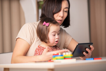 mother and child with down syndrome watch lessons on the tablet online