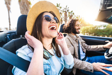 Happy couple driving convertible car enjoying summer vacation - Friends rent cabrio auto on holiday...