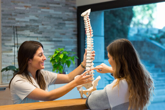 Female doctor pointing to the hernia on a spine model to a patient during a consultation at the physiotherapy center.