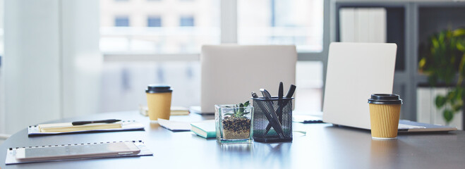 Ready for a busy business day. Shot of technology, takeaway coffee cups and office supplies on a desk in an empty office during the day.