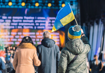 Child or kid with winter clothes and hat with Ukrainian colors. Protest against war in Ukraine