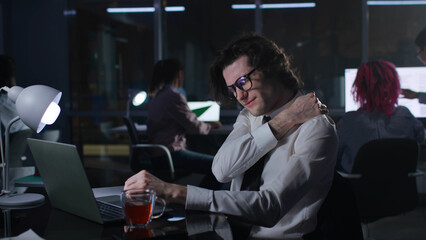 Businessman overwork and suffer from pain in neck sitting at desk in dark office