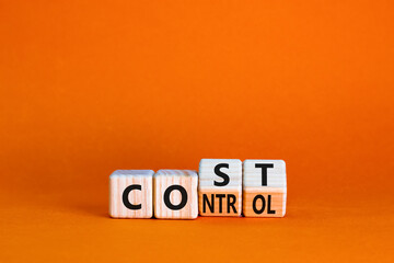 Cost control symbol. Turned wooden cubes and changed the concept word Cost to Control. Beautiful orange table orange background, copy space. Business cost control concept.
