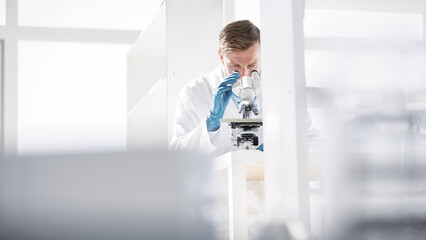 scientist looking at liquid samples through a microscope .