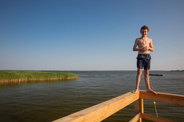 Fototapeta na wymiar Teenage boy is standing at the parapet of a pier