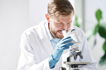 scientist looking at liquid samples through a microscope .