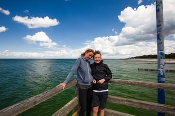 Fototapeta premium Mature woman and boy are standing on a wooden pier