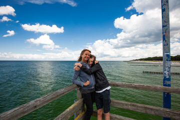 Mature woman and boy are standing on a wooden pier