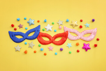 Holidays image of carnival party sequins masks over yellow background. view from above
