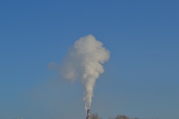 White smoke from a large chimney against the sky.