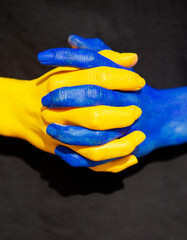 women's hands intertwined in fingers are painted in the yellow and blue colors of the Ukrainian flag. willingness to fight for freedom and national independence, strength, unity. Support Ukraine