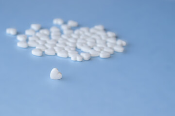 cute little heart shape pills on light blue background. empty space for text, copy paste. Medicines for the heart disease and for blood vessels , lungs. heart shape from little hearts or chaotic 