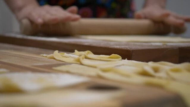 Flattening Dough With Rolling Pin. Twisted Angel Wings Dough In Foreground. selective focus