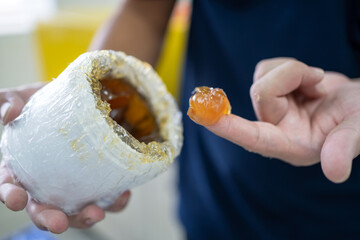 Worker use finger to scoop up lithium grease from white plastic can in the laboratory. Yellow...
