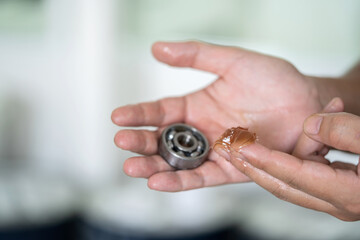 Worker use finger to put lithium grease into small bearing at laboratory. Yellow transparance...