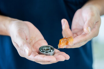 Worker use finger to put lithium grease into small bearing at laboratory. Yellow transparance...