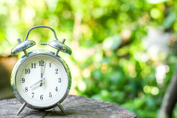 Silver vintage alarm clock show 8 o'clock on wooden table.