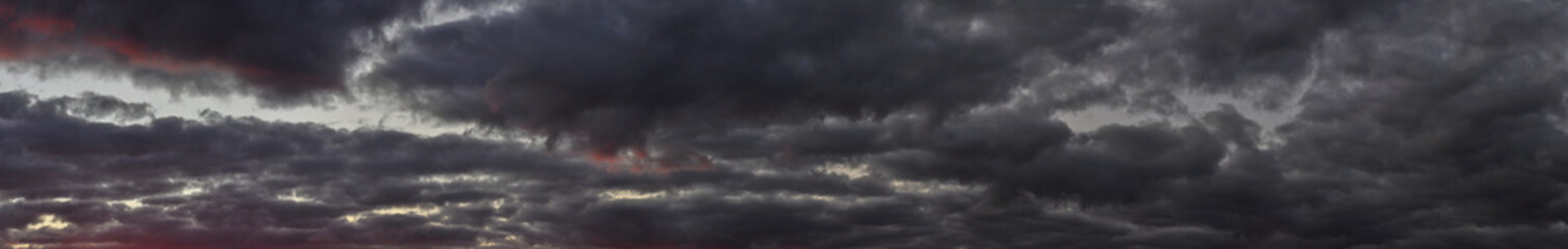 Panorama of a gloomy sky covered with dark clouds at sunset