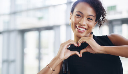 Doing what I love and loving what I do. Cropped shot of a young businesswoman showing a heart sign...