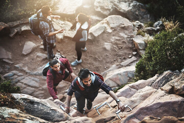 Making their way to the top. Shot of a group of friends climbing a ladder while hiking in the mountains.