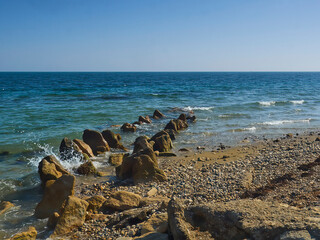 An unusual rock formation, resembling stegosaur spines, protruding from Spithead Beach and leading off through waves and sea to an open, wide horizon. © Das