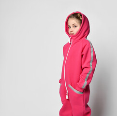 side view of a child girl in a fleece warm hooded suit with a hood and reflective stripes. the girl...