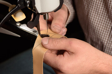 Industrial sewing machine in workshop of shoemaker. Bootmaker setting up professional sewing...