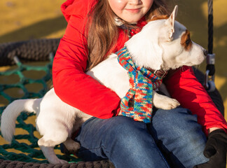 Happy child girl with dog. Portrait kid with pet Jack Russell Terrier outdoors - pet owner concept