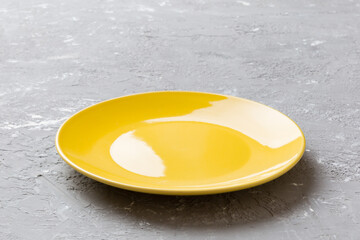 Perspective view of empty yellow plate on cement background. Empty space for your design