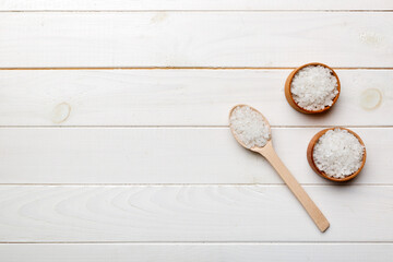 Fototapeta na wymiar A wooden bowl of salt crystals on a wooden background. Salt in rustic bowls, top view with copy space