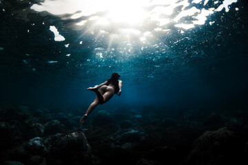 Chica joven en bañador buceando en el mar duranta un dia de verano.