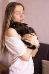 Young woman with adorable rabbit indoors, close up. Lovely pet and animal concept
