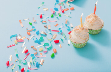 birthday hat with confetti and cupcake on blue paper background