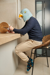 Man disguised as a bird mask draws on his digital tablet