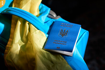 Ukrainian refugees luggage with passport and yellow-blue flag. Evacuation of civilians from Ukraine