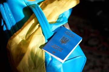 Ukrainian refugees luggage with passport and yellow-blue flag. Evacuation of civilians from Ukraine
