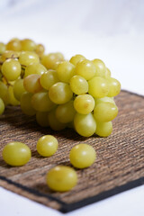 Green grapes with white background on wicker tablecloth.