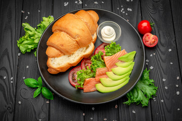 Sandwich. Croissant with salmon, cream cheese and vegetables