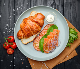 Sandwich. Croissant with salmon, cream cheese and vegetables